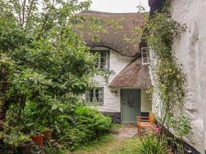 an old cottage with a thatched roof and a green door at 3 Cumberland Cottages in Kingsbridge