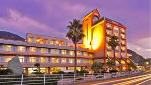 a large building with a palm tree in front of it at Boyokaku in Amakusa