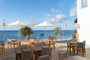 a restaurant on the beach with tables and umbrellas at Hani Boutique Hotel Phú Quý in Cù Lao Thu