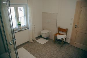 a bathroom with a toilet and a chair and a window at Ferienhaus Allmunzen in Witzmannsberg