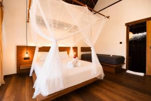 a bedroom with a bed with a mosquito net at Akar Mentawai in Simpatdegat