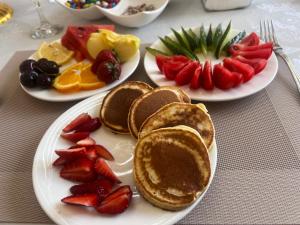 three plates of pancakes and fruit on a table at ERLAN Guest House in Jangy-Talap