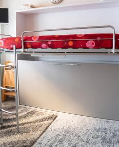a metal bunk bed with a red blanket on it at Studio cosy avec balcon et vue sur la montagne à Chamrousse - 19 m² in Chamrousse