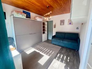 a living room with a blue couch in a room at Studio cosy avec balcon et vue sur la montagne à Chamrousse - 19 m² in Chamrousse