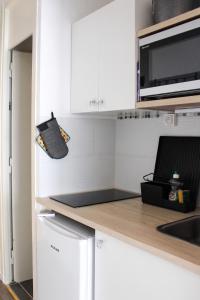 a kitchen with white cabinets and a counter top at Studio cosy avec balcon et vue sur la montagne à Chamrousse - 19 m² in Chamrousse +10 photos