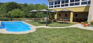 a swimming pool with an umbrella next to a house at Palleira da Meiroá in Esgos