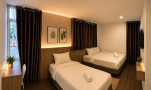 a hotel room with two beds and a window at Point Stay GH in Kuching