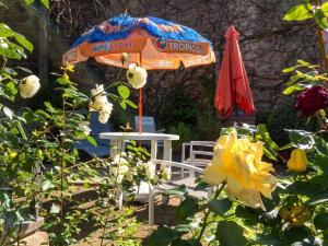 an orange umbrella and a white table and a white chair and a table at Charmant studio à Néris-les-Bains 20 m² avec jardin privé in Néris-les-Bains