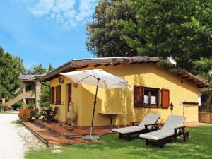a small yellow house with chairs and an umbrella at Charming house in Ramazzano - Le Pulci with shared pool in Ramazzano