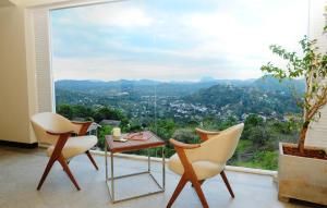 a room with chairs and a table and a large window at Skyloft Kandy by Aaradhya in Kandy