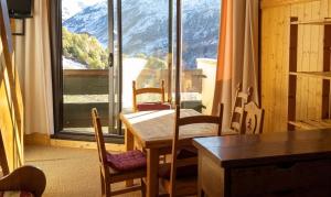 a dining room with a table and chairs and a large window at Appartement charmant à Les Menuires, 36 m², vue montagne. in Saint-Martin-de-Belleville
