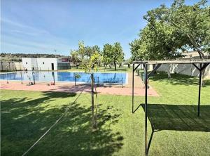 a swing set in the grass near a pool at One Apartamentos in Torreorgaz