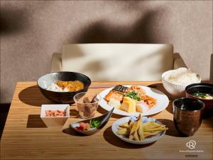 a wooden table with plates of food on it at Daiwa Roynet Hotel Tsukuba in Tsukuba