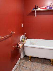 a bath tub in a bathroom with a red wall at Cosy lakeside chalet in Mashteuiatsh with jacuzzi in Mashteuiatsh +8 photos
