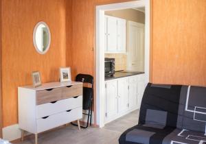 a bedroom with a white dresser and a kitchen at Appartement charmant à Plancher-les-Mines 40 m² avec jardin in Plancher-les-Mines