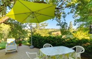 a table and chairs and an umbrella on a patio at Appartement avec piscine à Montpezat-de-Quercy 40 m² in Montpezat-de-Quercy