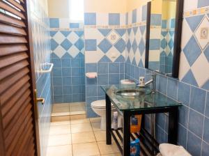 a blue tiled bathroom with a sink and a toilet at Appartement confortable à Deshaies avec vue sur la mer - 55 m² in Deshaies