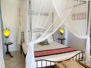a bedroom with a canopy bed with curtains at Appartement confortable à Deshaies avec vue sur la mer - 55 m² in Deshaies