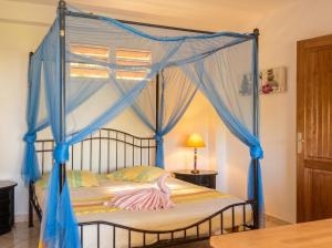 a bedroom with a canopy bed with blue drapes at Appartement confortable à Deshaies avec vue sur la mer - 55 m² in Deshaies +14 photos