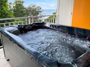 a hot tub on a balcony with water at Appartement confortable à Deshaies avec vue sur la mer - 55 m² in Deshaies