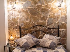 a bedroom with a stone wall and a bed with two pillows at Charming Villa with Private Pool in La Calzada de Béjar in La Calzada de Béjar