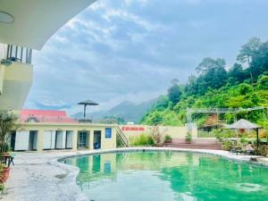 a pool in front of a building with mountains in the background at Heaven Hill Hotel & Hot Spring in Cham Ta Lao