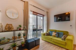 a living room with a green couch and a clock at Avenue View Rooms in Porto +42 photos