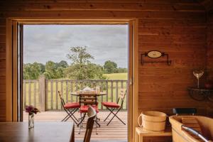 an open door to a deck with a table and chairs at Cabane Pomme d'Amour in La Chapelle-Bouexic
