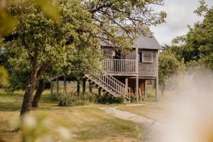 a house with a porch and stairs to a deck at Cabane Pomme d'Amour in La Chapelle-Bouexic