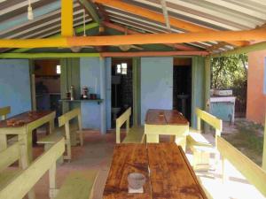 a patio with wooden tables and chairs with a roof at Hostel Lo de Milton in Barra de Valizas