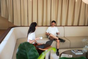 a man and a woman sitting on a couch with a laptop at Les Maritimes in Seignosse
