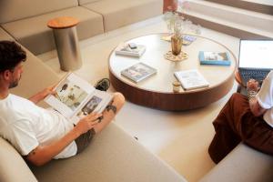 a man sitting on a couch reading a book at Les Maritimes in Seignosse