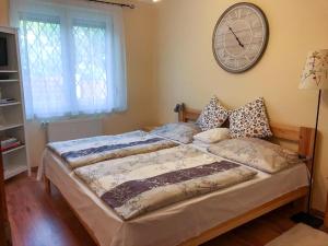 a bed in a bedroom with a clock on the wall at Lily House in Balatonvilágos
