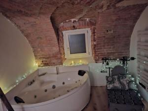 a bath tub in a room with a brick wall at Villa Lu alloggio con idromassaggio e piscina in Carignano +25 photos
