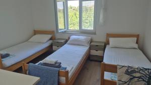 two twin beds in a room with two windows at Apartmani Loli in Ugljan