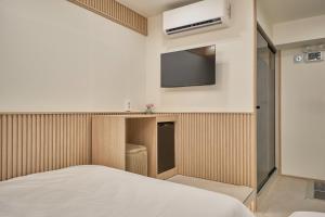 a bedroom with a bed and a tv on the wall at ZIP 1972 DDP two-min from airport bus station 4-min from DDP subway station in Seoul
