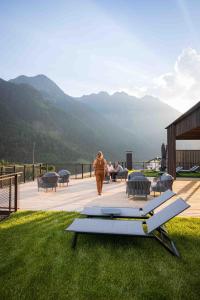 a woman walking on a deck with mountains in the background at My Mountain Moments - Adults Only 12 plus in Selva dei Molini