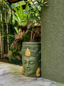 a green statue of a head sitting next to a wall at The Lodge Canggu in Tumbak Bayuh +53 photos