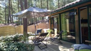 a patio with an umbrella and chairs on a deck at Maison, Piscine sous les pins in Moliets-et-Maa