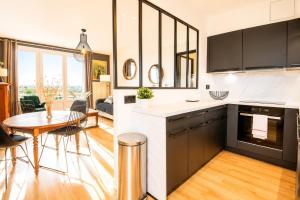 a kitchen with black and white cabinets and a table at Black and White - Joli appart à Tours in Joué-lès-Tours