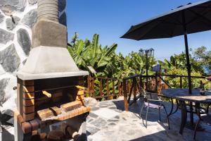 a outdoor fireplace with a table and an umbrella at TenoHomes La Era de Catuja Getaway in Los Realejos