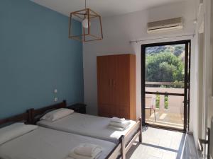two beds in a room with a large window at Apokoros Craft Deco Apartments & Studios in Kalyves