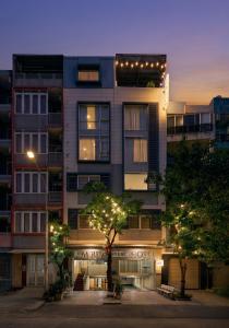 a tall building with lights in front of it at Elm Riverside Hotel by Urban B in Ho Chi Minh City