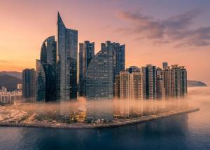 a city skyline with tall buildings in the water at Haeundae Marine Capsule Hotel&Spa in Busan