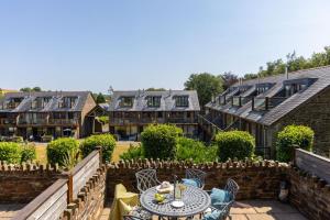 a patio with a table and chairs and buildings at Keepers Cottage - Dartmouth Golf and Spa Resort in Dartmouth