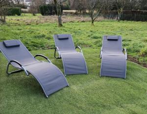three metal benches sitting on the grass in a field at Gite de l'etoile in Rocroi