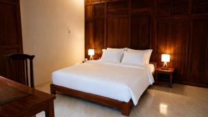 a bedroom with a large white bed with two lamps at Villa Kebun Pala in Borobudur