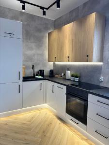 a kitchen with white cabinets and black appliances at Apartament Kaszubska Bryza III - HEL in Hel +20 photos