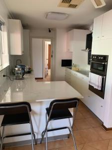 a kitchen with a white counter and two chairs at Nice quite stay in Perth