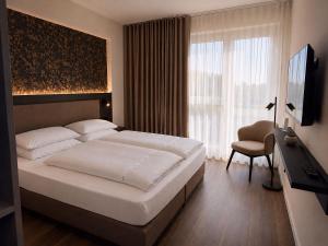 ein Schlafzimmer mit Bett, Fernseher und Stuhl in der Unterkunft in2 The Hotel in Xanten + 26 Fotos